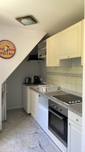 A kitchen with white cabinets, a granite countertop, a stove, and a coffee maker. - APPARTEMENT DUPLEX RESIDENCE DU PARC (Saint-Nectaire)