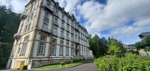Ein historisches Gebäude mit mehreren Etagen, großen Fenstern und einem zentralen Eingang mit Stufen.