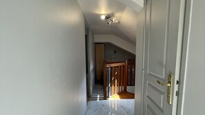 A hallway with a marble floor leading to a staircase and a door with a brass handle. - APPARTEMENT DUPLEX RESIDENCE DU PARC (Saint-Nectaire)