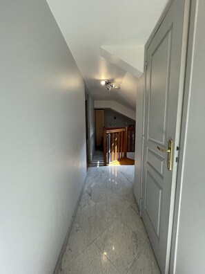 A hallway with a marble floor leading to a staircase and a door with a brass handle. - APPARTEMENT DUPLEX RESIDENCE DU PARC (Saint-Nectaire)