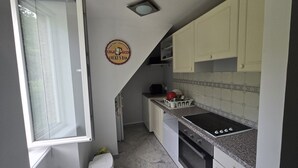 A compact kitchen with a stove, oven, and a window. - APPARTEMENT DUPLEX RESIDENCE DU PARC (Saint-Nectaire)