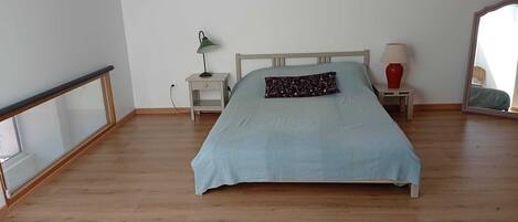 A bedroom with a bed, a nightstand, a lamp, and a mirror.