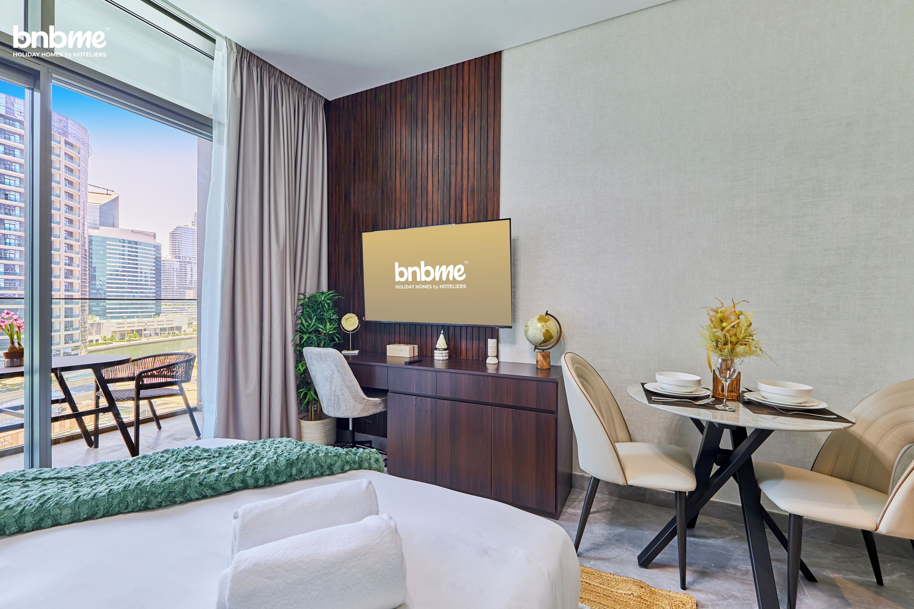 Une chambre d’hôtel moderne dotée d’une grande fenêtre, d’un téléviseur à écran plat, d’un coin repas et d’un lit.