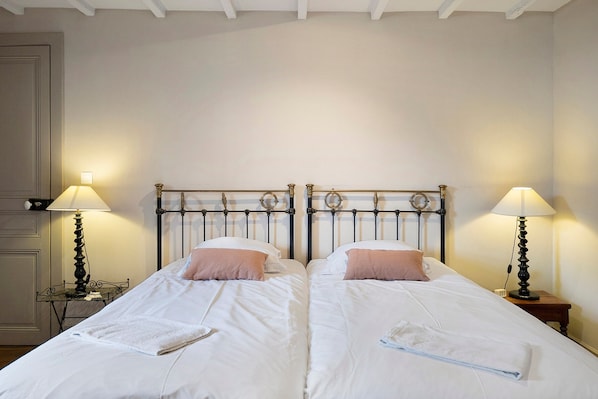 A double bed with a metal headboard, two bedside lamps, and a white wall.