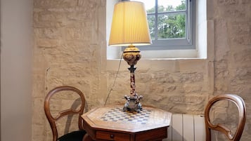 Una mesa de madera con mantel a cuadros, una lámpara de pie con base decorativa y dos sillas con respaldo curvo.