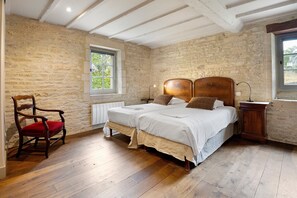 A bedroom with a wooden bed, a chair, a bedside table, and a window.