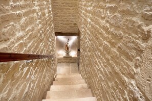 Un escalier avec des murs en pierre menant à une statue.