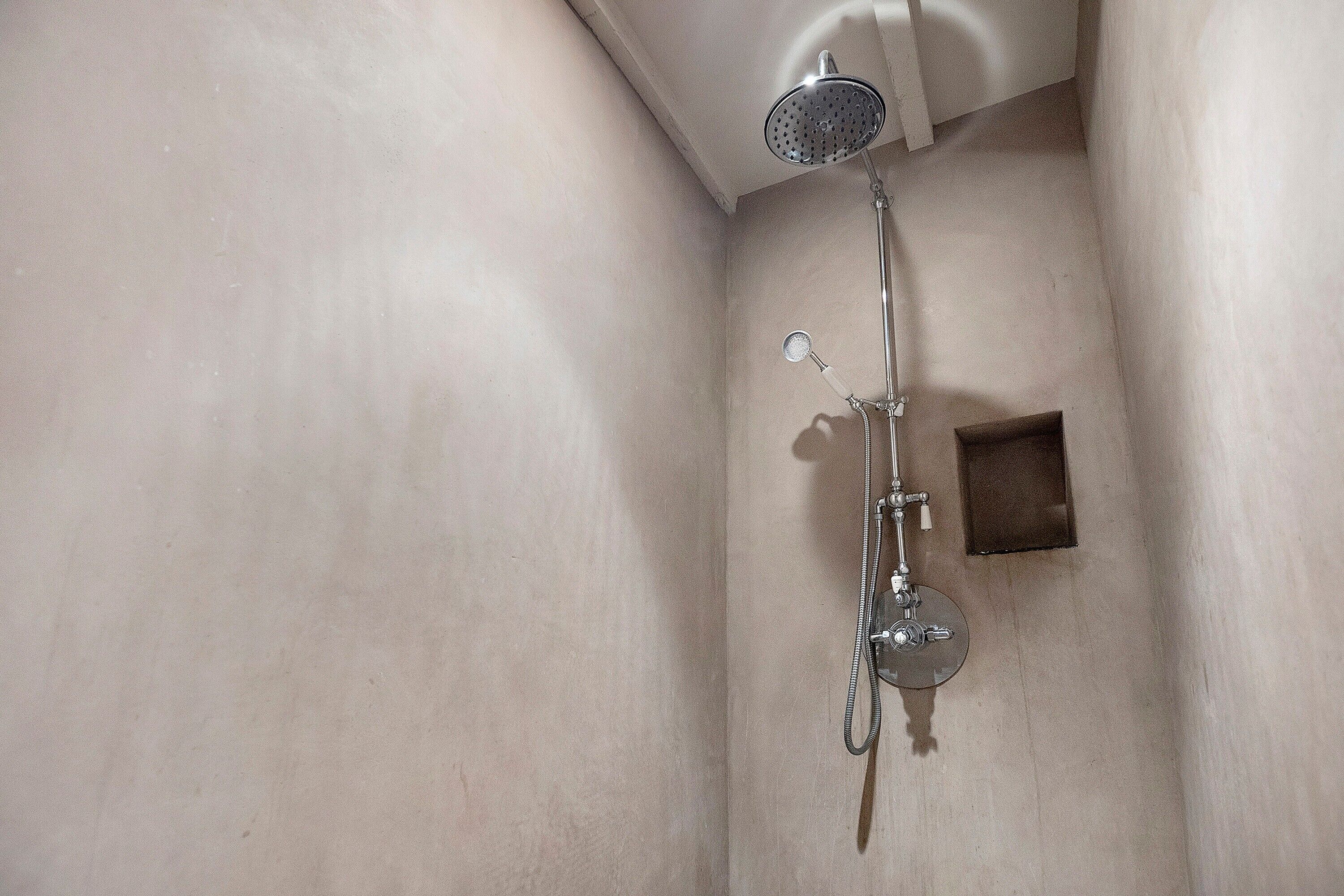 Een douche met een handdouche en een kraan op de muur.