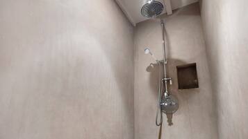 Een douche met een handdouche en een kraan op de muur.