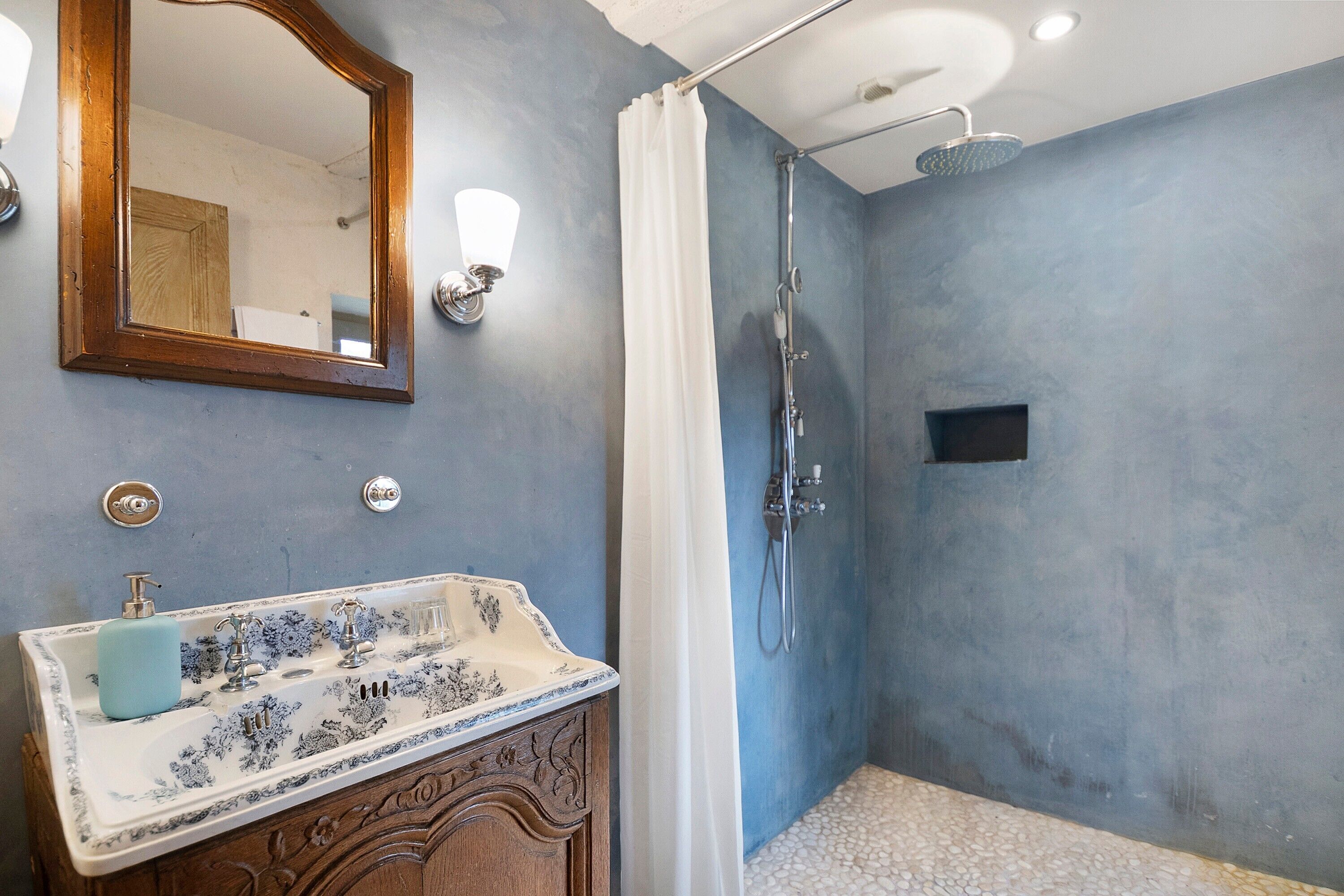 Un baño con un lavabo antiguo, una ducha y un espejo.