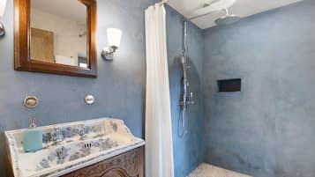 Un baño con un lavabo antiguo, una ducha y un espejo.