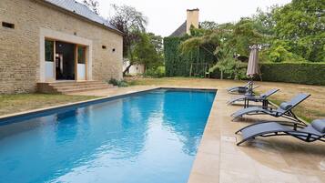 Une piscine avec des chaises longues et, en arrière-plan, un bâtiment en briques.