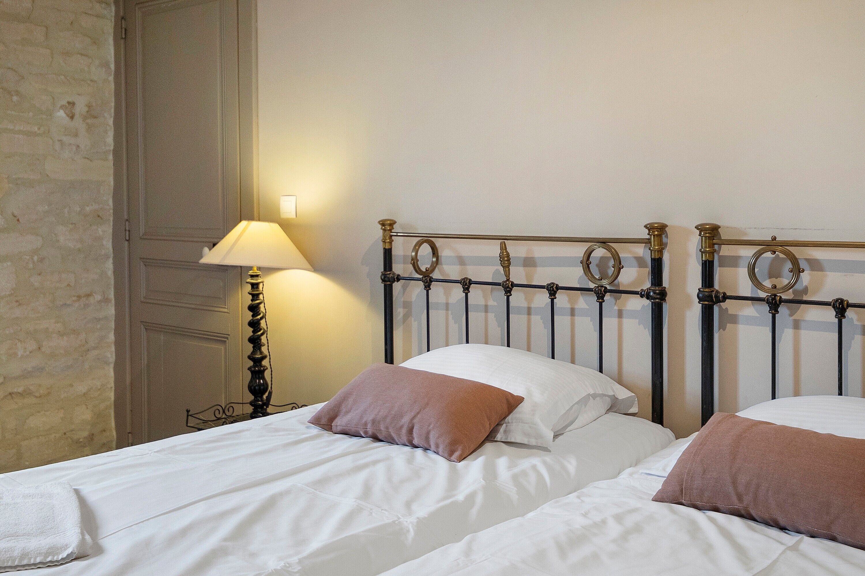 Habitación de hotel con dos camas, una lámpara y una pared con textura decorativa.