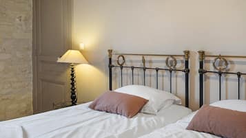 Habitación de hotel con dos camas, una lámpara y una pared con textura decorativa.