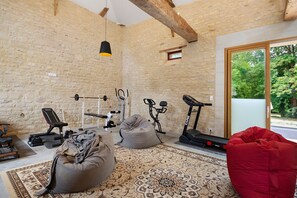 A home gym with exercise equipment, a patterned rug, and a large window. - Cottage "La Ferme" with Lake View, Private Terrace, and Wi-Fi (Ponts sur Seulles)