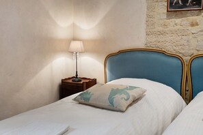 Ein Schlafzimmer mit zwei Betten, einem Nachttisch mit Lampe und einer Steinwand.