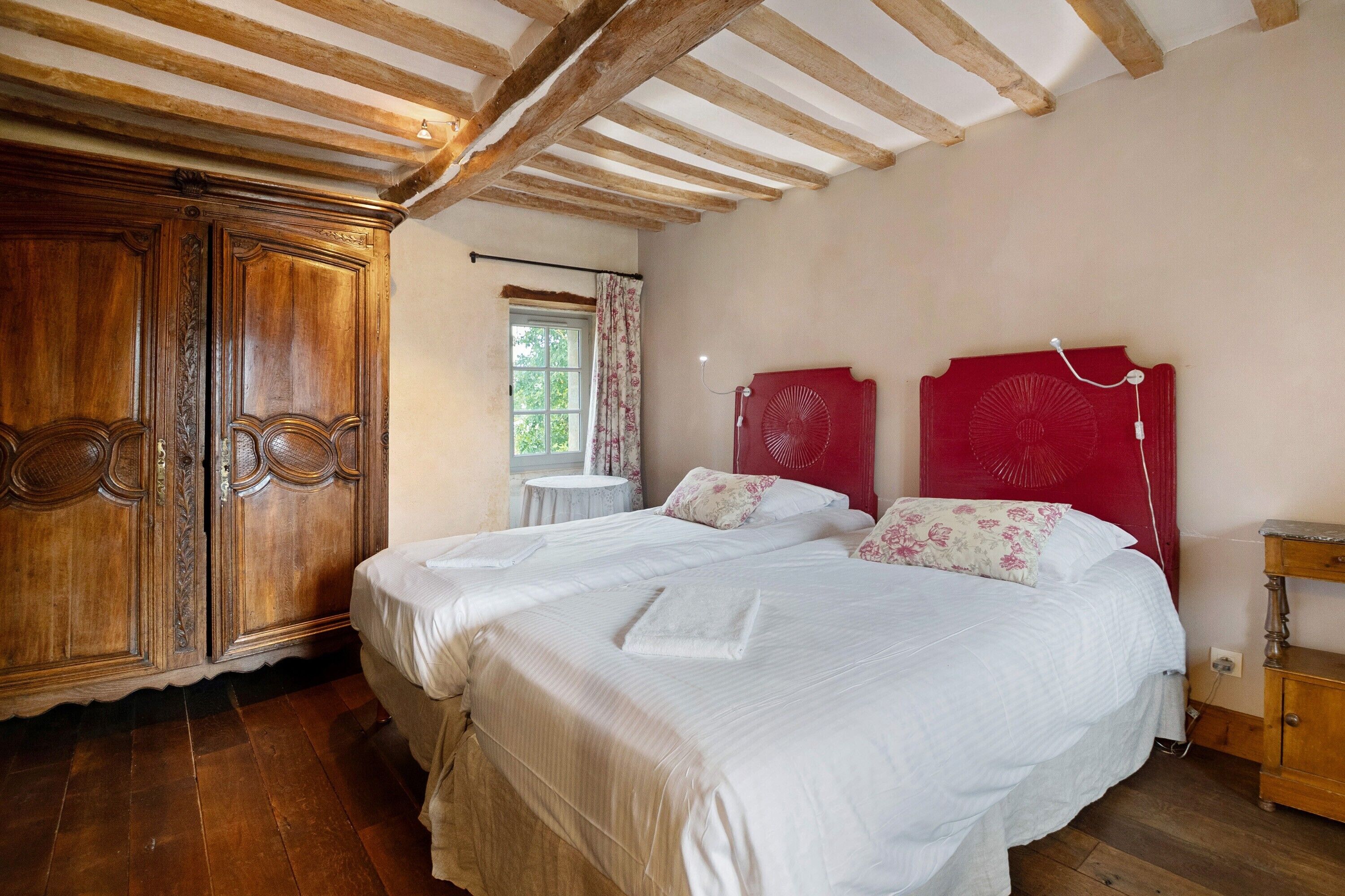 Un dormitorio con dos camas, un armario de madera y ventana con vistas a zonas verdes.