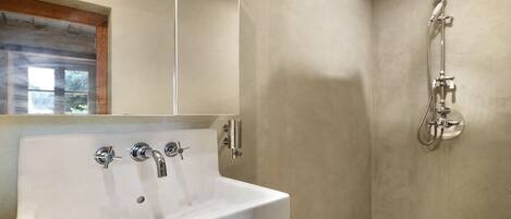 Un baño con lavamanos blanco, un espejo y una ducha con cabezal de ducha de mano.