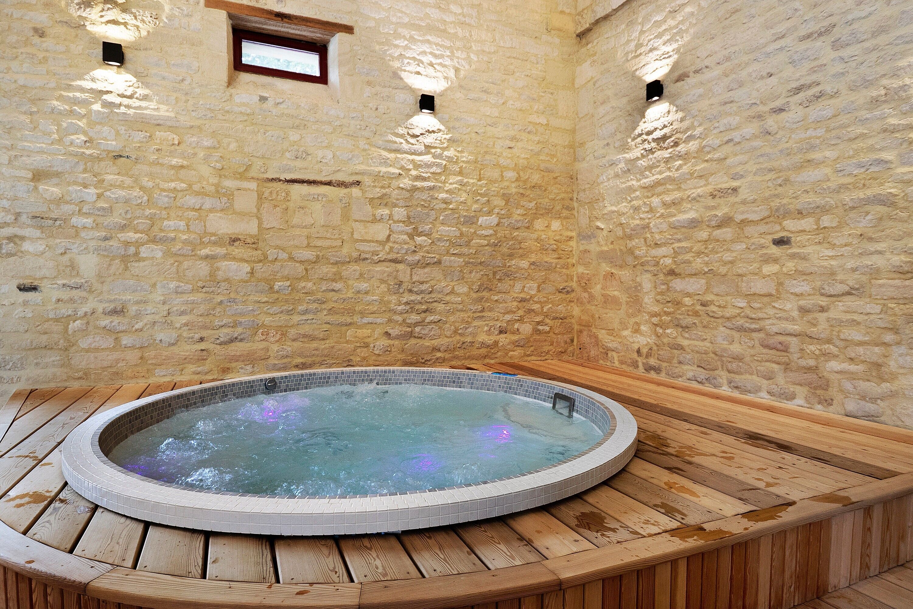 A stone-walled room with a circular hot tub.