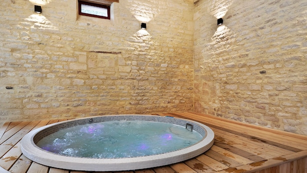Een kamer met stenen muren en een rond bubbelbad.