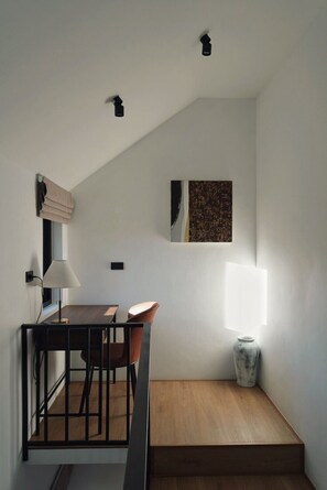 Un intérieur moderne avec un escalier, un coin repas comprenant une table et des chaises, une lampe et une œuvre d’art accrochée au mur.