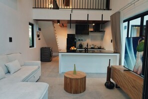 Ein modernes Wohnzimmer mit einer Couch, einem runden Holztisch und einer Küchenzeile mit Kochinsel.