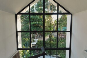A room with a large window offering a view of a garden and a building labeled 'The Langan and Organic'. - Le Lamoon - Private Pool Villa Near Ban Tai Beach (Surat Thani)