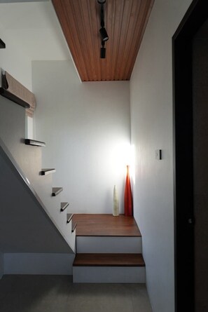 Un escalier avec des marches en bois et un design moderne, menant à une porte sombre.