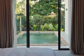 A room with a large window overlooking a swimming pool and lush greenery. - Le Lamoon - Private Pool Villa Near Ban Tai Beach (Surat Thani)