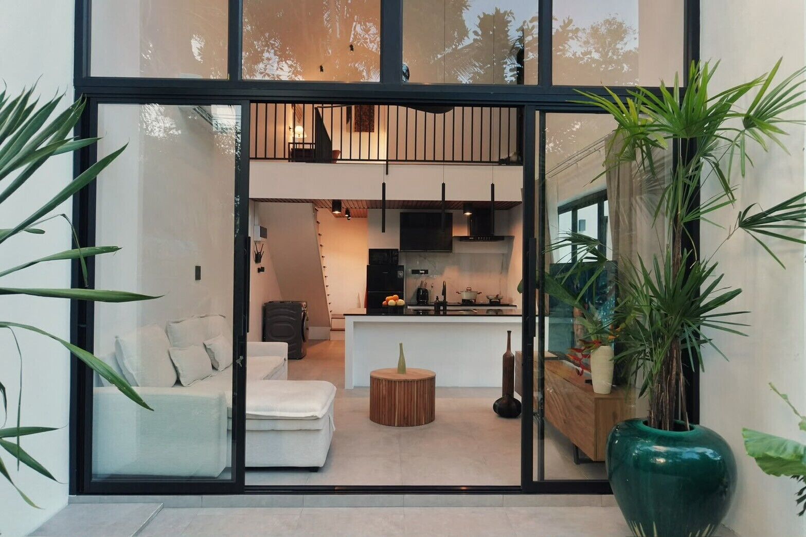 A modern interior with a sofa, a dining table, and a kitchen area visible through a glass partition.