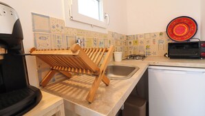 Eine Küche mit Holzregal, Spüle, Toaster und Geschirrgestell.