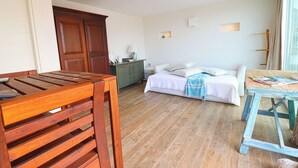 Ein Zimmer mit einem Bett, einem Holztisch, einem Schminktisch und einem Fenster mit Vorhängen.