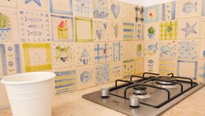 Eine Küche mit einem Gasherd, einer weißen Tasse und einer gefliesten Spritzschutzwand mit verschiedenen Mustern.
