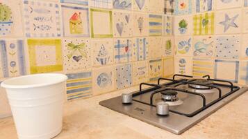 A kitchen with a gas stove, a white cup, and a tiled backsplash with various designs.