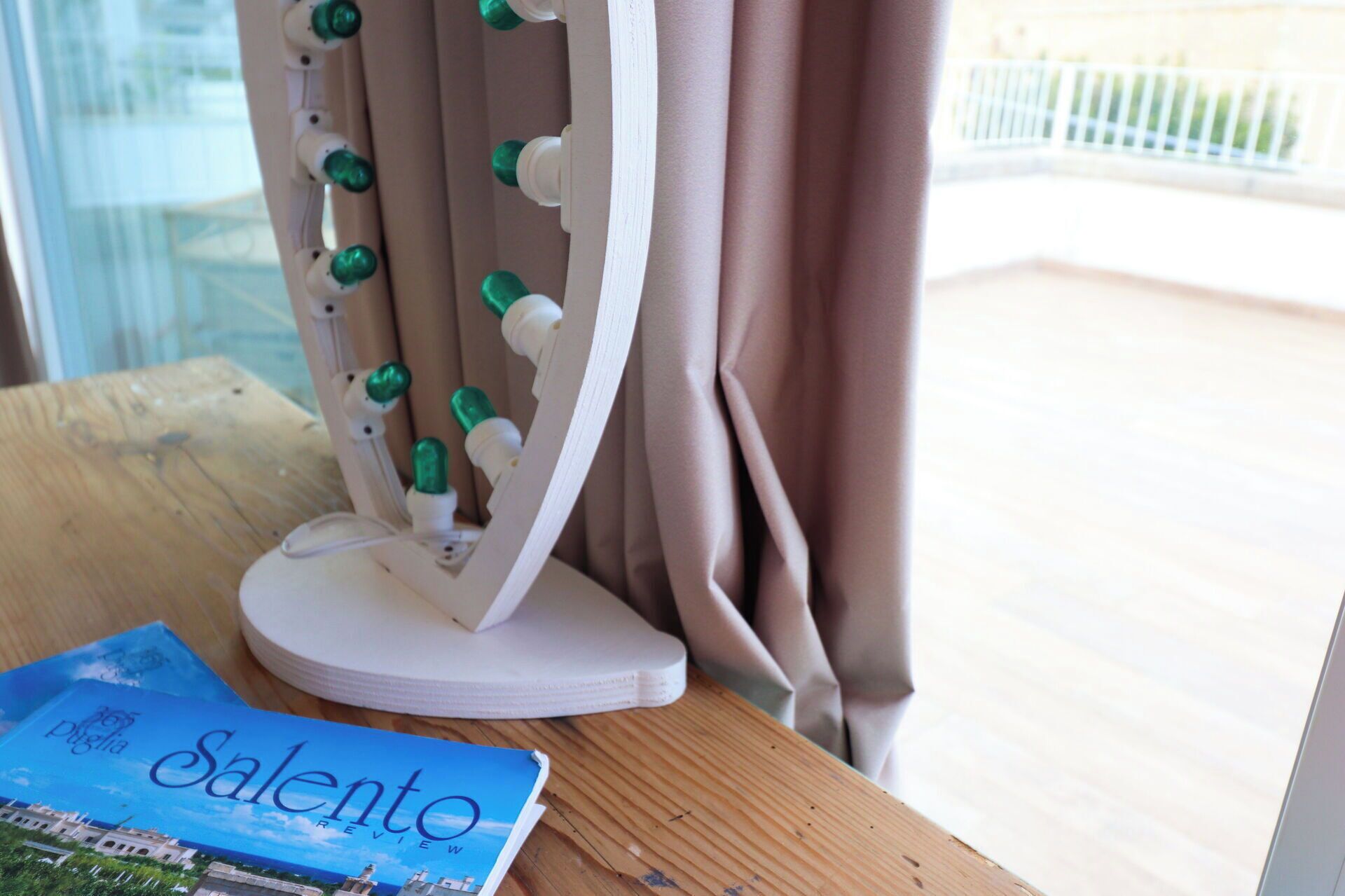 A wooden table with a white vanity mirror and a book titled 'Salento Review.'