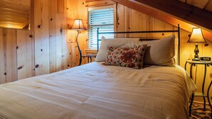 Ein Zimmer mit Holzwänden, einem Bett, zwei Nachttischlampen und einer Uhr auf einem Nachttisch.