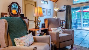 Ein gemütliches Wohnzimmer mit zwei Sesseln, einem Tisch mit Lampe und einem Bücherregal.