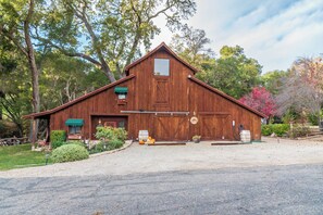 A wooden barn-style building with a porch, a garage, and a driveway. - King Studio + Kitchenette | Oak Hills + 30 Min to Coast | Room With A View (Paso Robles)