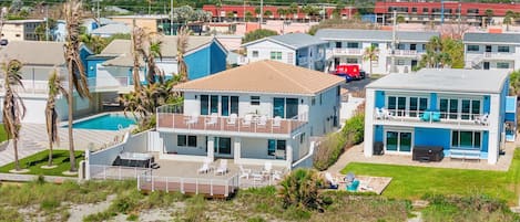 A beachfront property with a pool, multiple balconies, and a view of the ocean.