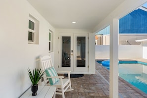 A covered patio with a pool, white walls, and a door leading to a pool area. - 755 S Atlantic Ave (Cocoa Beach)