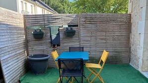 A patio with a table and chairs, surrounded by a wooden fence and a green artificial turf. - Air-conditioned “La Grange” House with Private Terrace, Wi-Fi, and AC (Azay-le-Rideau)