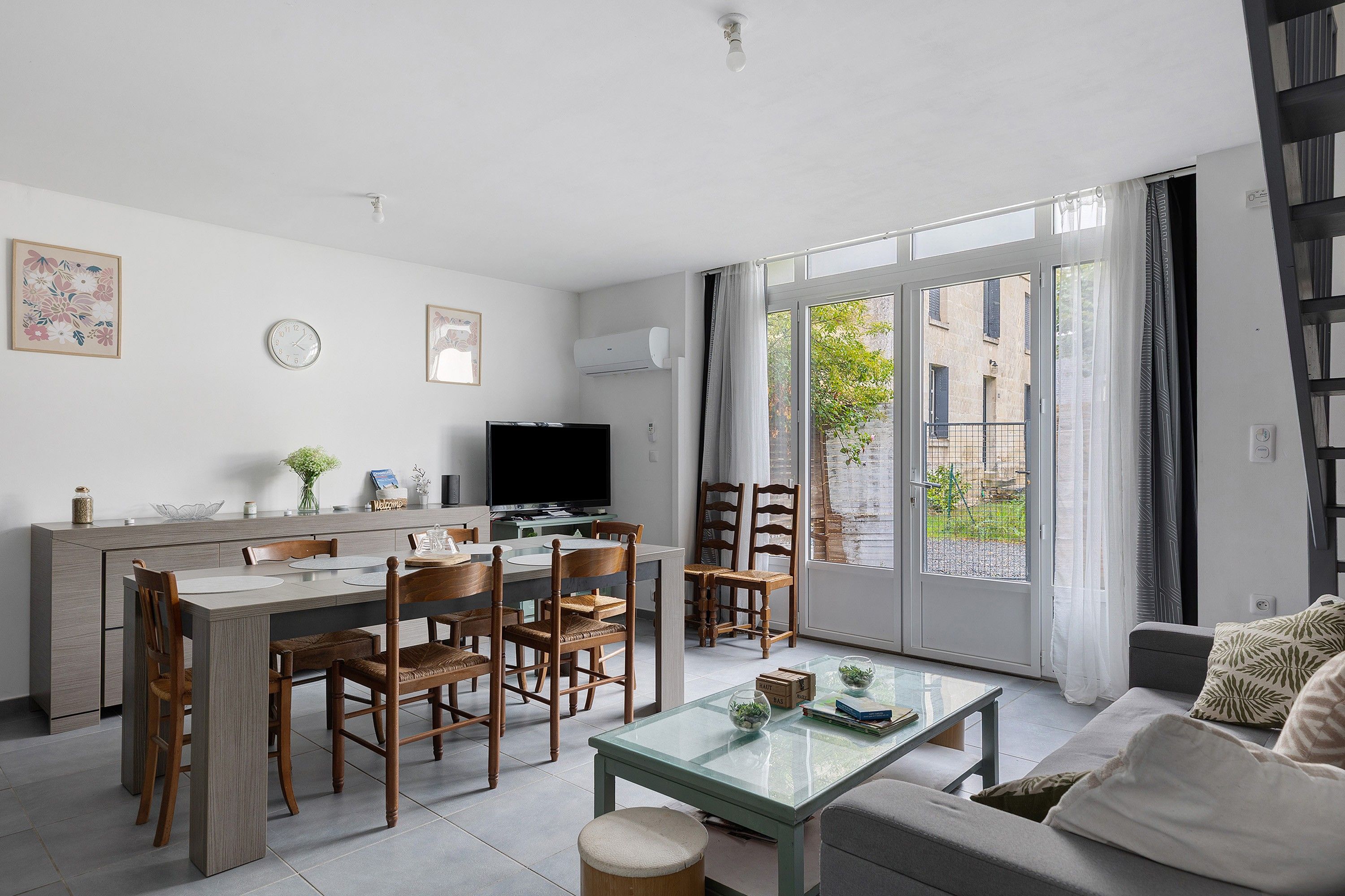 A modern living room with a dining area, a television, and a large window.