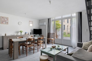 A modern living room with a dining area, a television, and a large window.