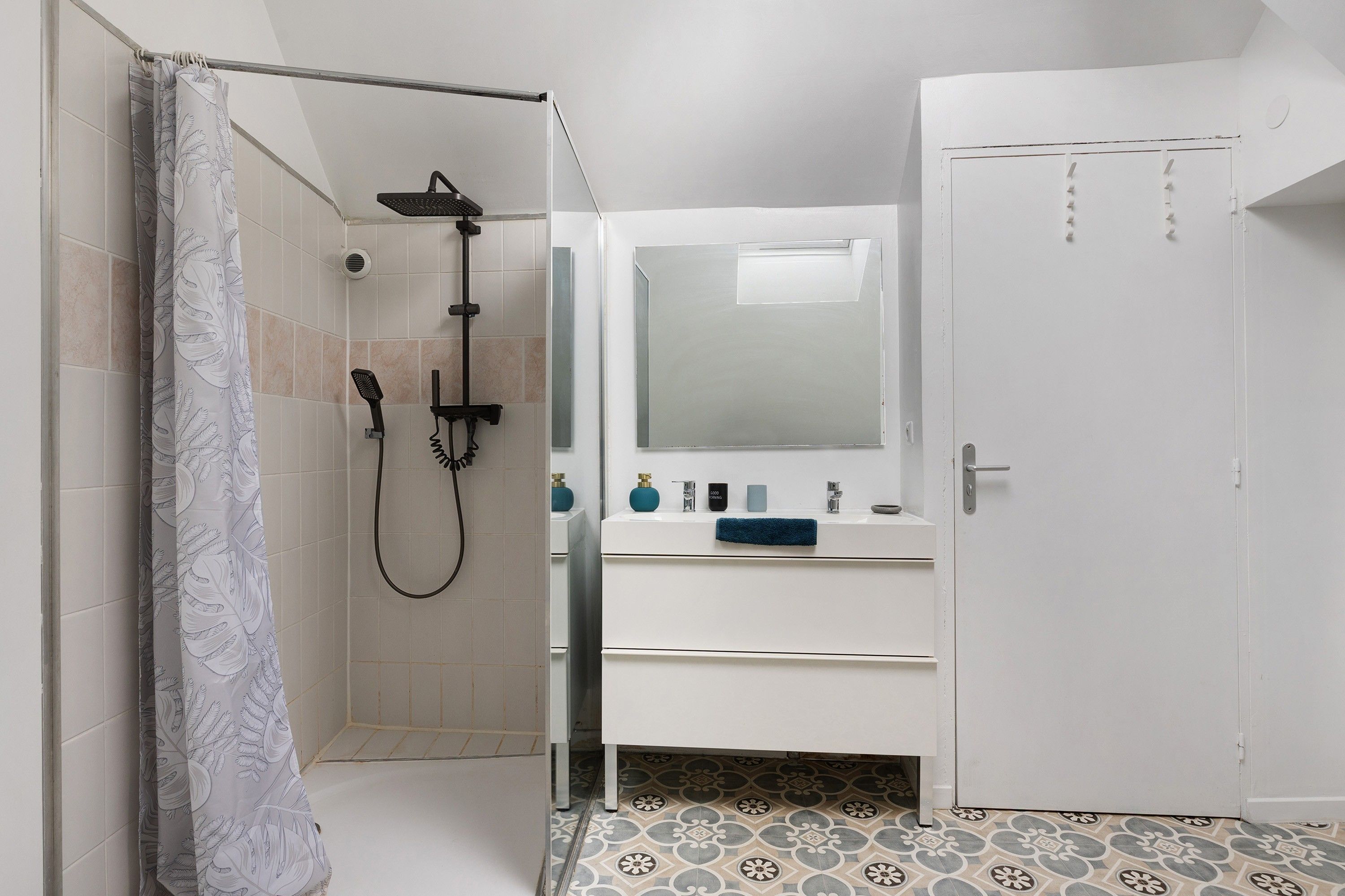A bathroom with a shower, a mirror, and a sink with toiletries.
