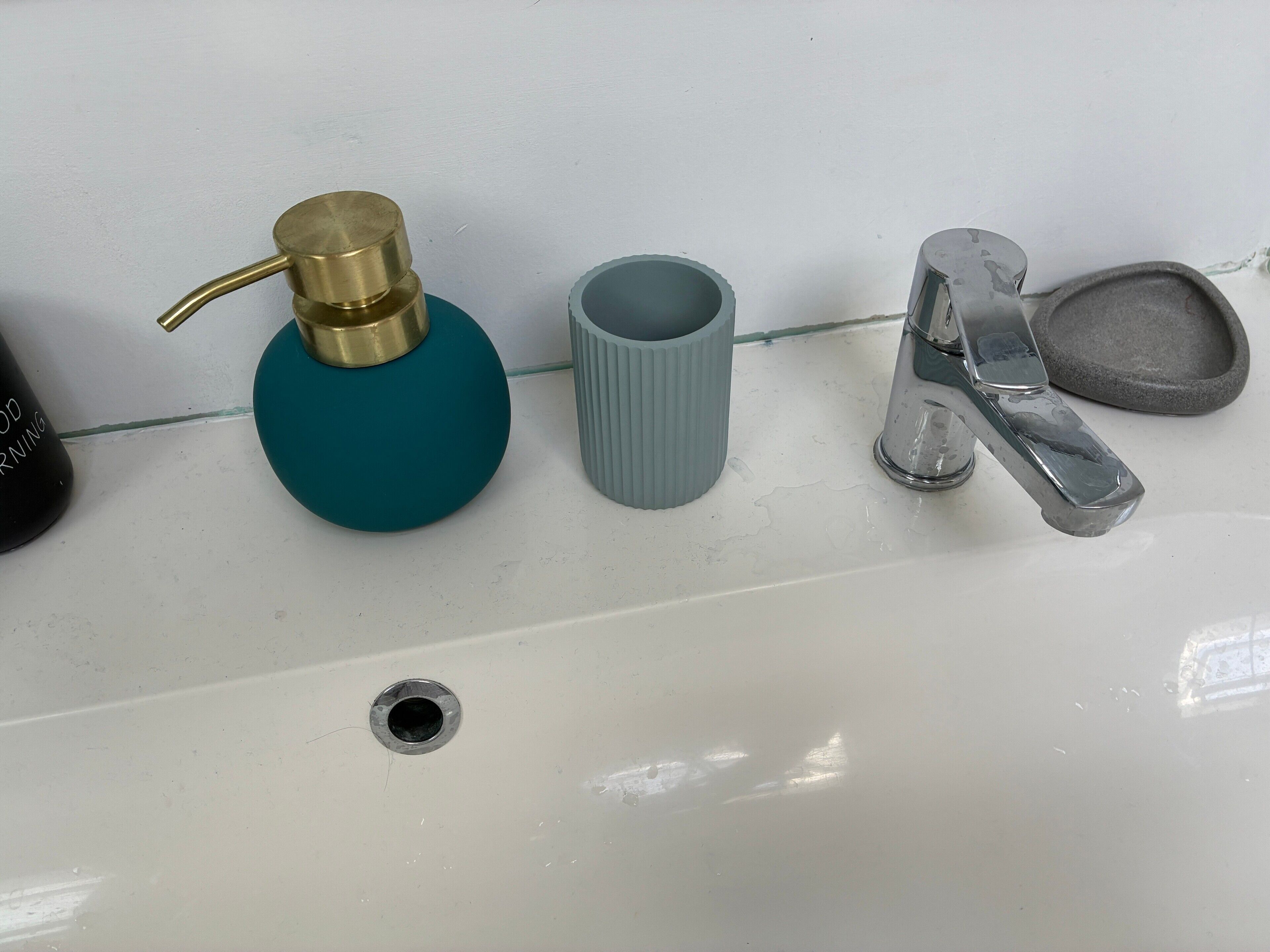 Ein Waschtisch mit Wasserhahn, Seifenspender und Zahnbürstenhalter.