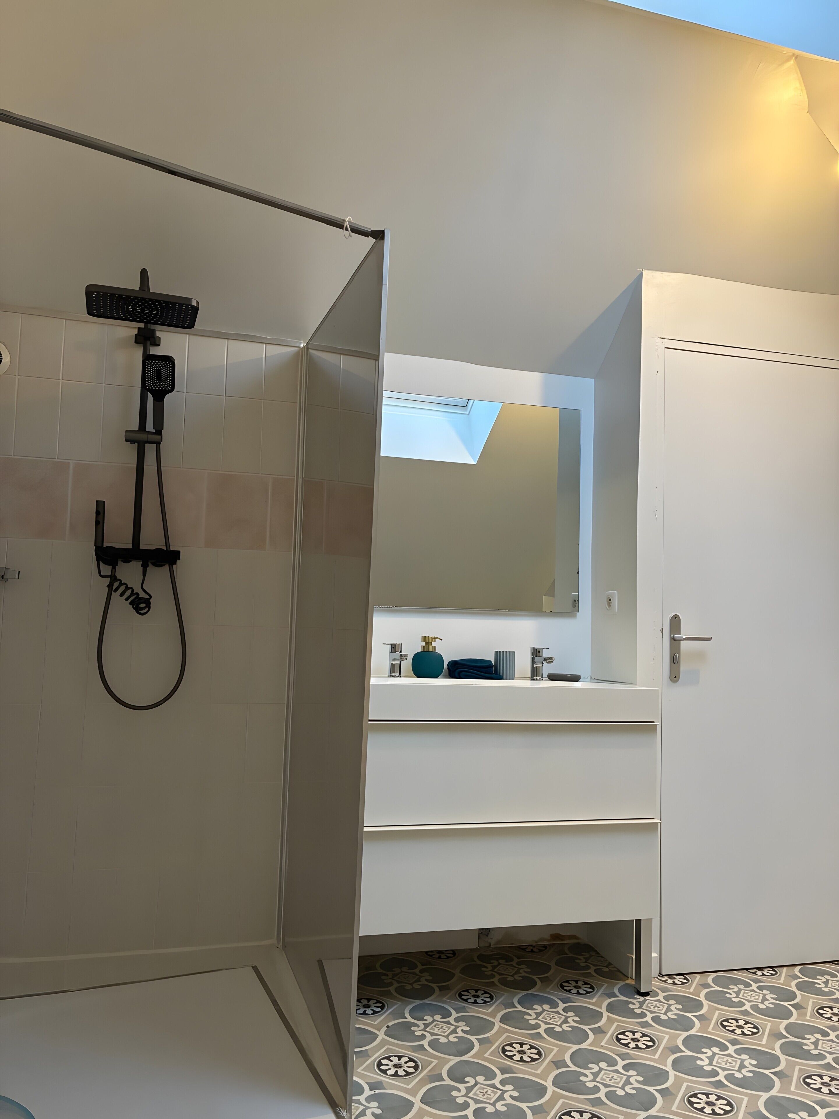 Une salle de bain avec une douche, un lavabo et un miroir.