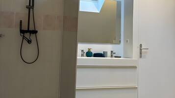 Une salle de bain avec une douche, un lavabo et un miroir.