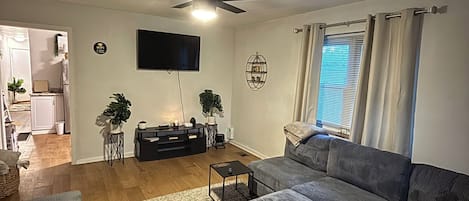 A living room with a sofa, a coffee table, a TV, and a ceiling fan.
