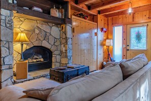 A cozy room with a stone fireplace, a wooden sofa, and a window with blinds.
