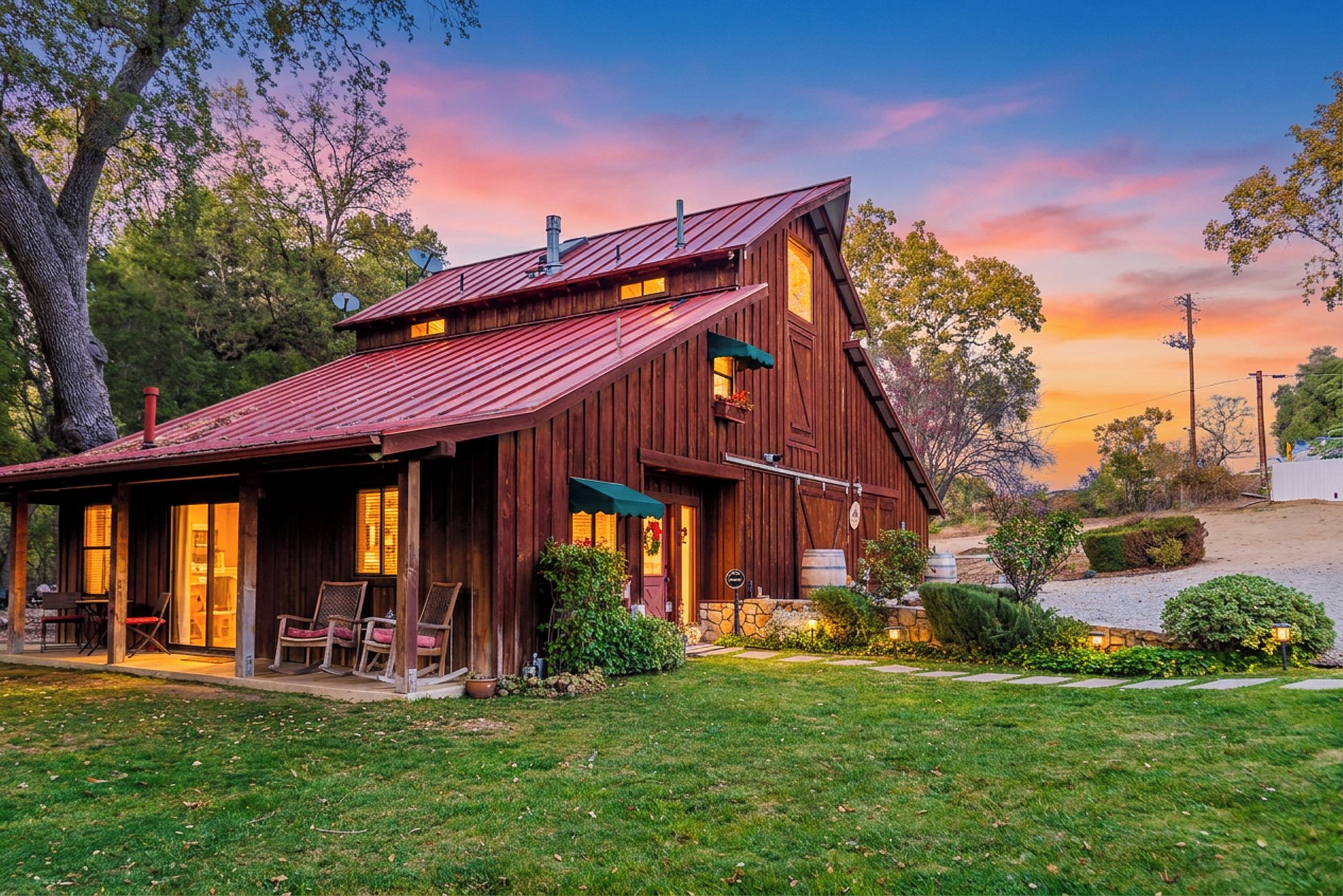 A rustic wooden cabin with a sloped roof, a porch with seating, and a stone foundation.